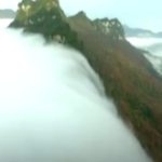 O mare de nori formeaza o cascada ce curge peste munti